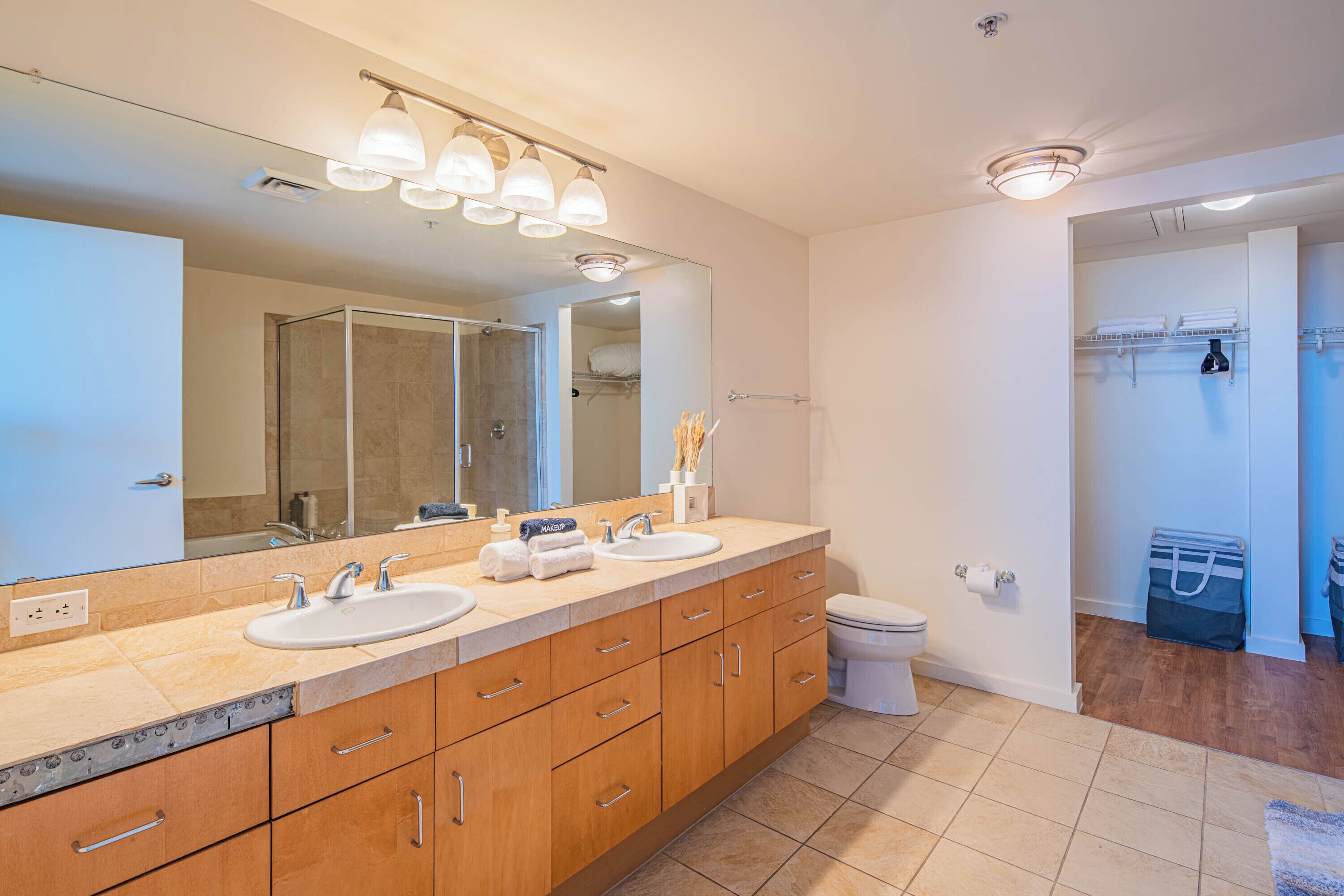 A modern bathroom with a double sink vanity, a large mirror, and a walk-in shower.