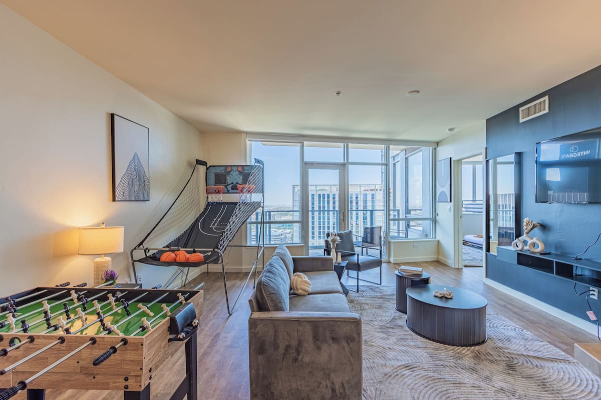 A modern living room with a foosball table, a sofa, a coffee table, and a TV.