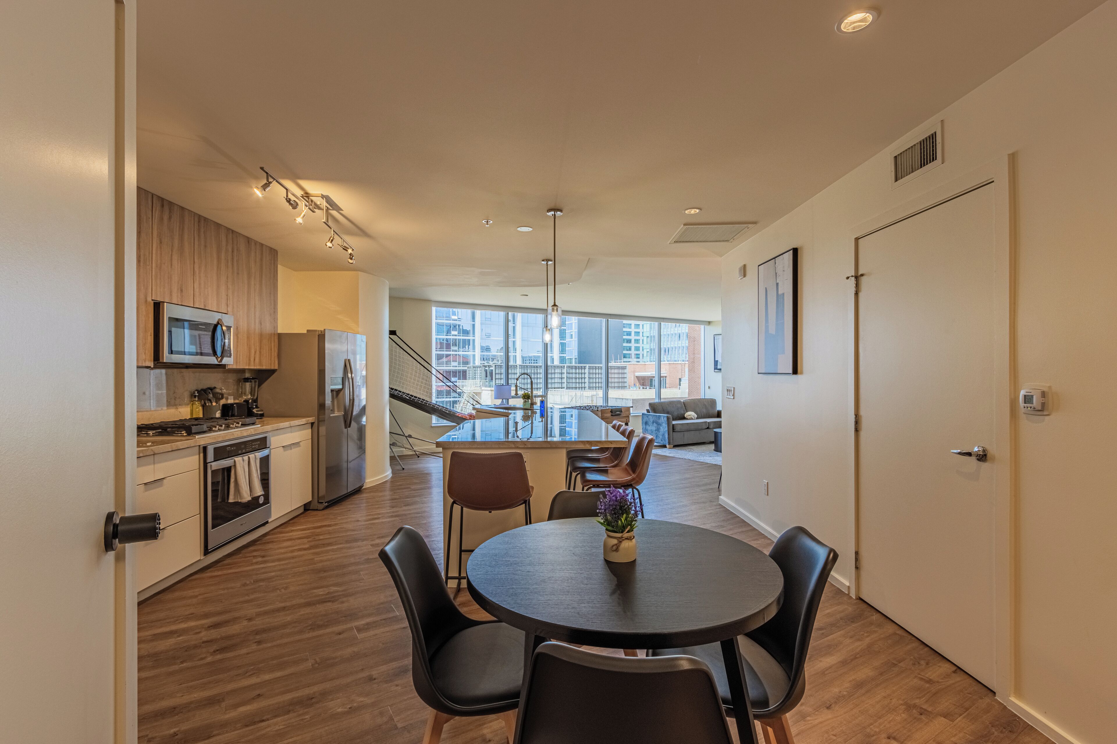 A modern kitchen with a dining area, large windows, and a view of the city.