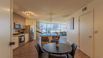 A modern kitchen with a dining area, large windows, and a view of the city.