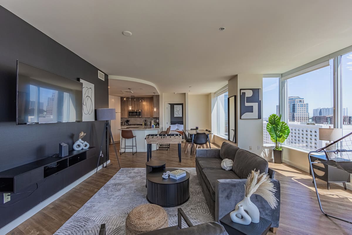 A modern living room with a sofa, coffee table, and a view of the city through large windows.
