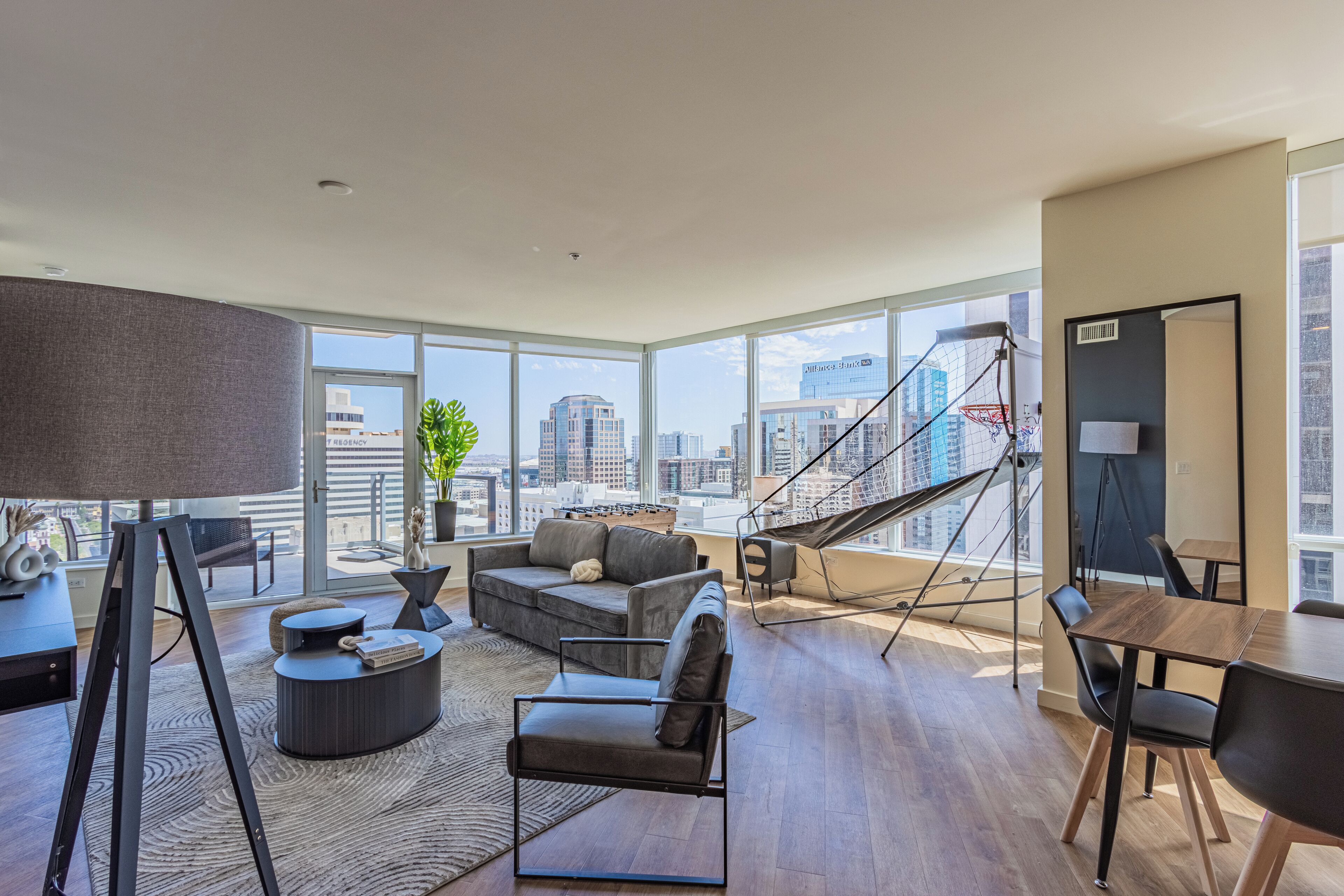 A modern living room with a large window, a sofa, a coffee table, and a dining area.