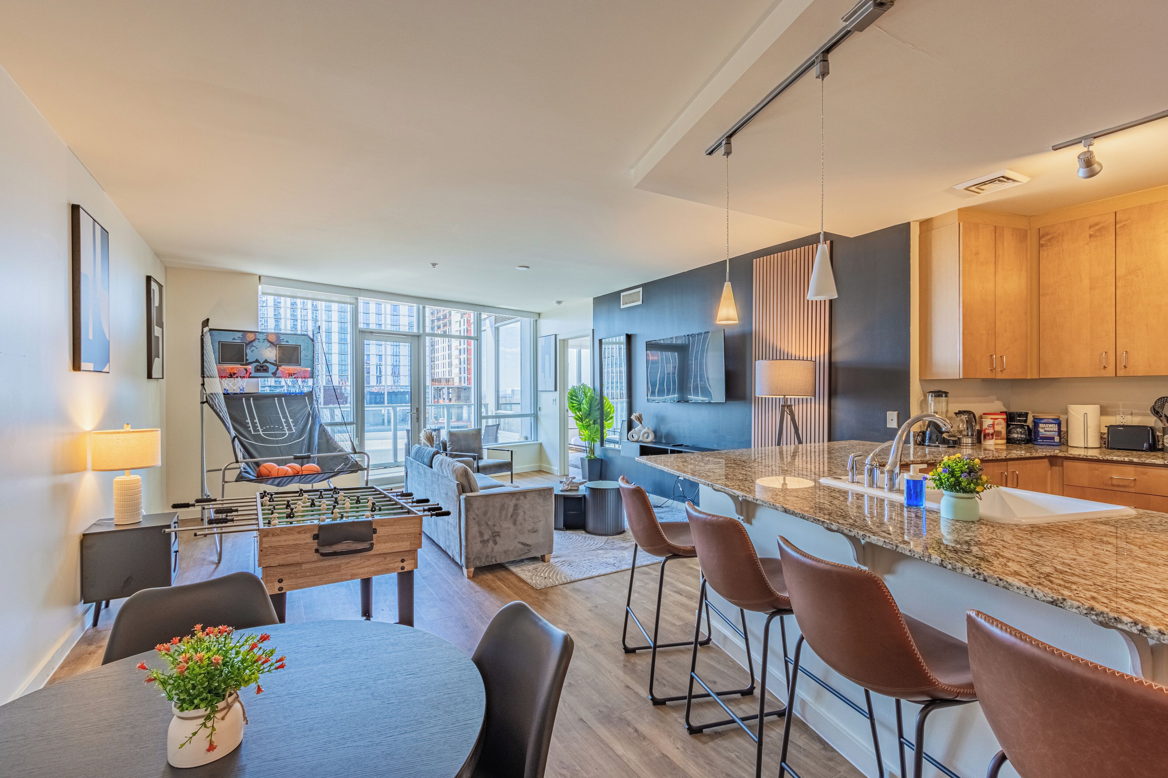 A modern kitchen with a large island, bar stools, and a foosball table.
