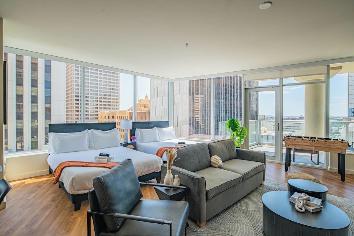 A hotel room with a large bed, a sofa, a coffee table, and a foosball table.