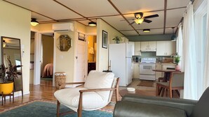 A living room with a sofa, a chair, a dining table, and a kitchen area with cabinets and appliances. - Mountain and Water View at Charming 2-bedroom Retreat in Sequim (Sequim)