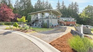 A two-story house with a covered porch, a fenced yard, and a gravel driveway. - Mountain and Water View at Charming 2-bedroom Retreat in Sequim (Sequim)