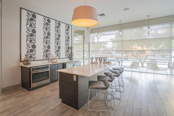 Una cocina moderna con una isla central, taburetes de bar y un amplio ventanal con vista a coches estacionados.