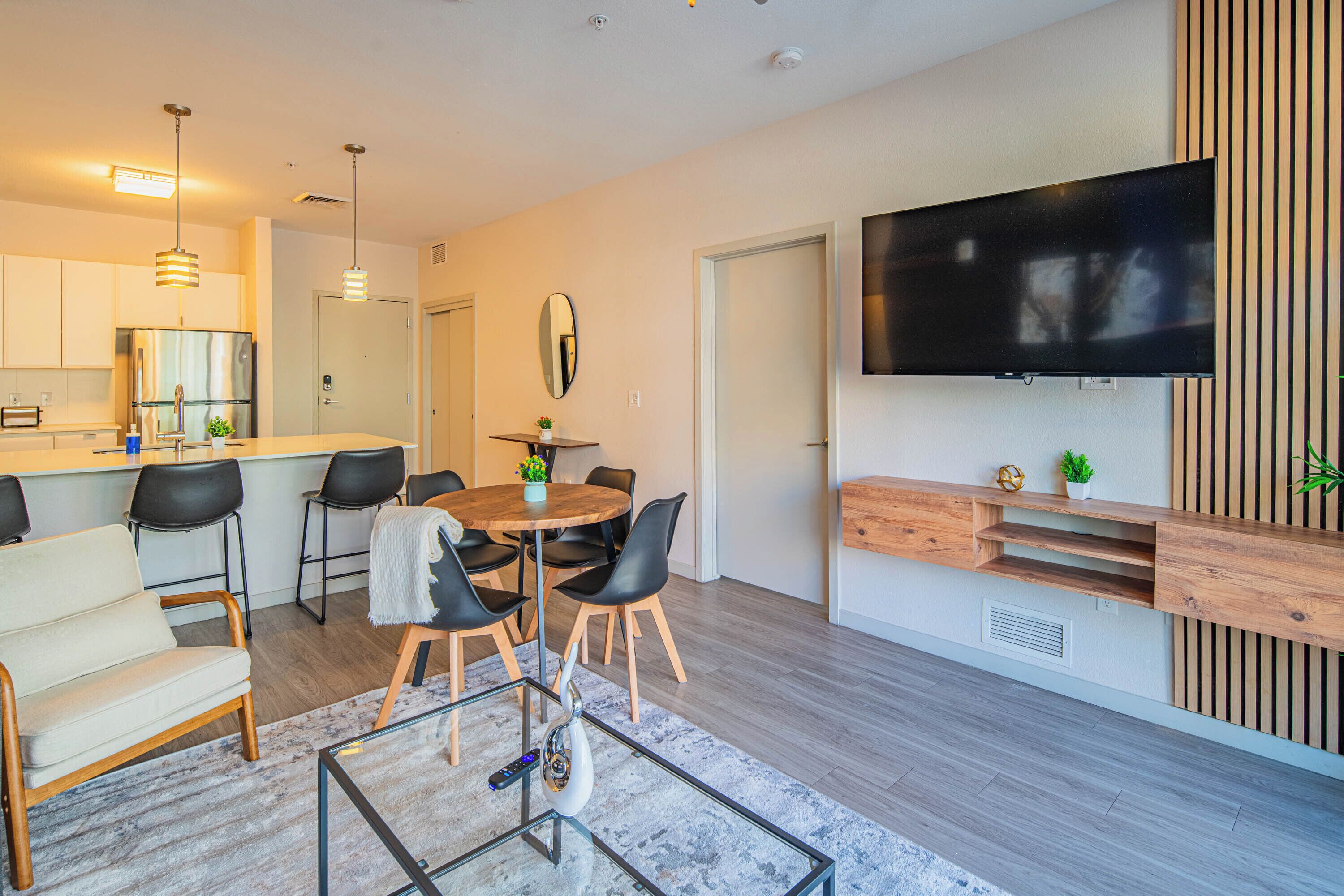 A modern kitchen with a central island, bar stools, and a dining area with a round table and chairs.