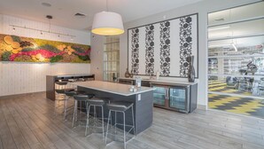 Une cuisine moderne dotée d’un îlot central, de tabourets de bar, d’un luminaire suspendu et d’œuvres d’art décoratives murales.