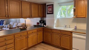 A kitchen with wooden cabinets, a countertop, a sink, a coffee maker, and a dishwasher. - Cozy 3-bedroom garden level, dog friendly, in the heart of Greeley (Greeley)