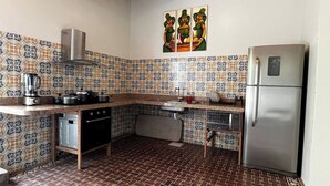 A compact kitchen with patterned tiles, a stainless steel refrigerator, and a coffee maker.
