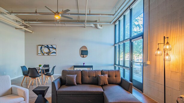 A modern living room with a sectional sofa, a glass coffee table, and a dining area with chairs and a table. - ROVE LIVING/KL - The Fredrick Tempe (Tempe)