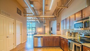 A modern kitchen with stainless steel appliances, wooden cabinets, and a central island. - ROVE LIVING/KL - The Fredrick Tempe (Tempe)