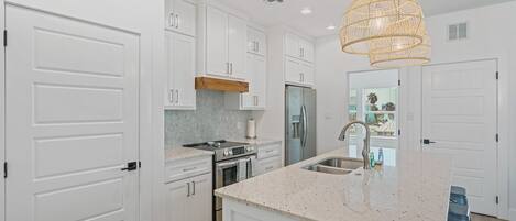 A modern kitchen with white cabinetry, a central island, and a hanging light fixture.