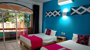 A hotel room with two beds, a balcony with chairs, and a blue accent wall. - Casa Cacaluta (Santa María Huatulco)
