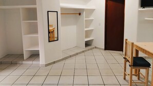 A room with white walls, tiled floor, wooden furniture, and built-in shelving. - Casa Cacaluta (Santa María Huatulco)