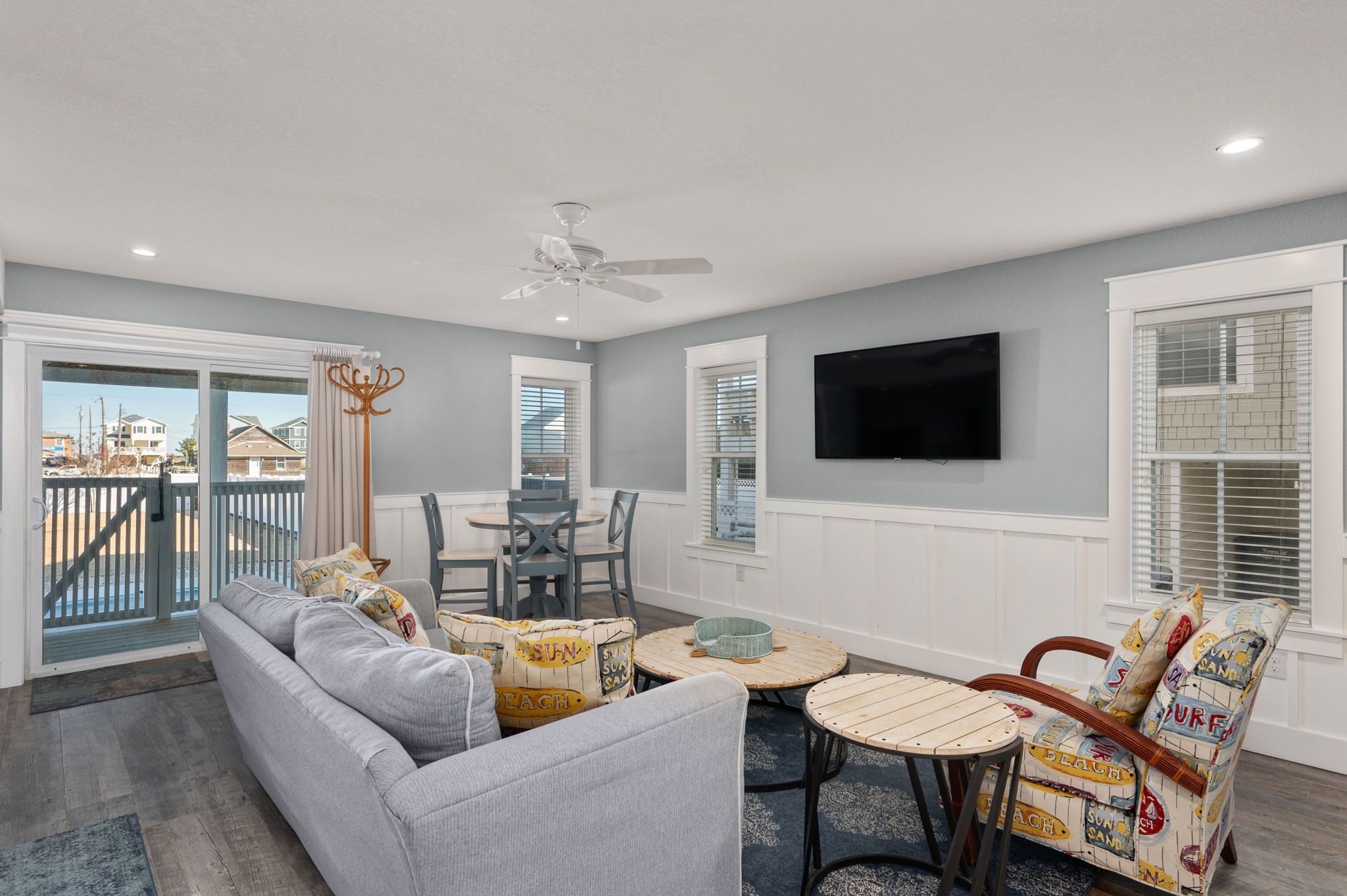 A living room with a gray sofa, a wooden coffee table, a patterned armchair, and a ceiling fan.