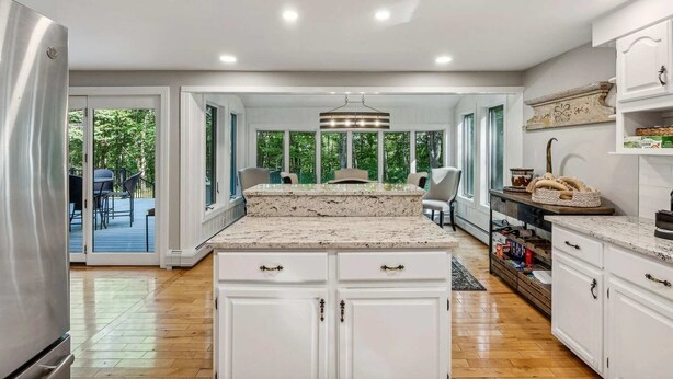 Una cocina amplia con armarios blancos, encimera de granito y vistas al exterior.