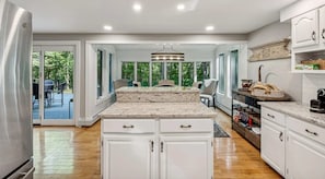 Una cocina amplia con armarios blancos, encimera de granito y vistas al exterior.