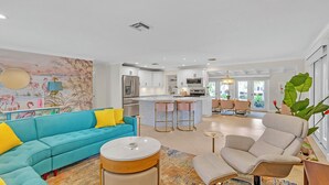 A modern living room with a teal sofa, a round coffee table, and a beige armchair. - Flirty Flamingo: Colorful Waterfront Escape w/ Pool (Wilton Manors)