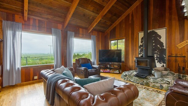 A cozy living room with a leather sofa, a television, and a fireplace.