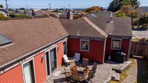 Une maison rouge avec une terrasse, un patio avec une table et des chaises, et une cheminée.