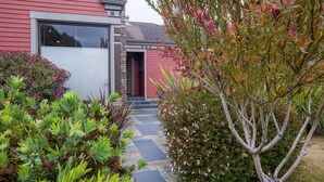 Une maison avec un garage, un pilier en pierre et une variété de plantes et d’arbustes.