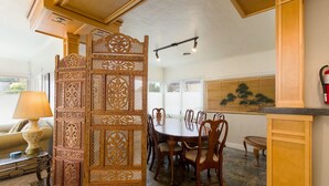 Un coin repas avec une table et des chaises en bois, un paravent décoratif et une peinture japonaise traditionnelle accrochée au mur.