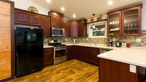 A modern kitchen with wooden cabinets, stainless steel appliances, and a tiled backsplash.