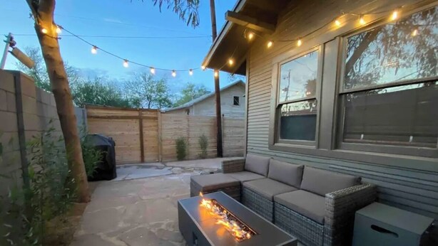 Eine Terrasse mit Feuerstelle, Gartenmöbeln und Lichterkette.