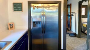 Ein Edelstahl-Kühlschrank mit Wasserspender, ein kleines gerahmtes Bild und ein Schild darüber.