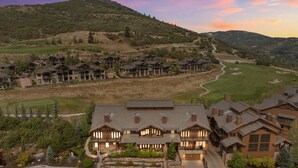 Una zona residencial con varias casas de dos pisos, un campo de golf y un paisaje montañoso al fondo.