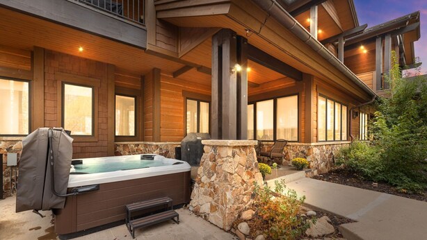Un jacuzzi y zona de estar exterior con paredes de piedra y vigas de madera.