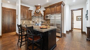 Una cocina con armarios de madera, una isla central con asientos, electrodomésticos de acero inoxidable y un salpicadero de piedra.