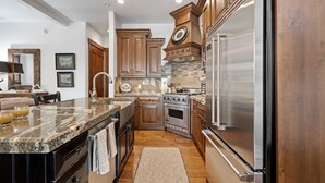 Una cocina moderna con encimeras de granito, electrodomésticos de acero inoxidable, armarios de madera y horno empotrado.