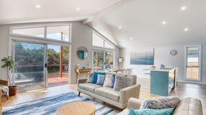 A spacious living area with a large sofa, a dining table, and a kitchen area.