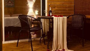 A cozy wooden cabin with a dining area featuring two chairs, a table with a white tablecloth, and a bottle of wine. - BeHappy Glamping (Medellín)