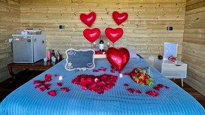 A cozy room with a wooden ceiling, a bed with a blue bedspread, and heart-shaped balloons. - BeHappy Glamping (Medellín)