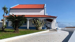 A two-story building with a red-tiled roof and a covered patio area.
