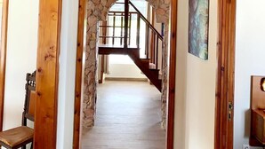 A wooden interior with a stone archway leading to a staircase.