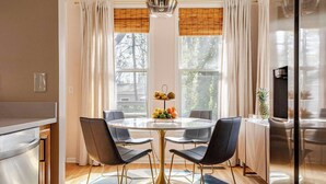 A modern kitchen with a round dining table, four chairs, a fruit bowl, and a refrigerator. - Spacious 3-bedroom house on the Beltline in Atlanta (Atlanta)