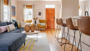 A modern living room with a sofa, coffee table, and chairs, a dining area with a table and chairs, and a wooden door. - Spacious 3-bedroom house on the Beltline in Atlanta (Atlanta)
