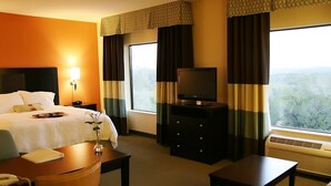 Een hotelkamer met een bed, een televisie op een dressoir, een bureau en een stoel.