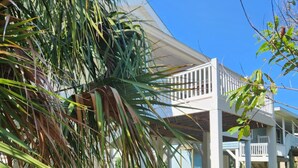 A covered outdoor area with a white structure, palm trees, and a clear blue sky. - Spacious Beach House Steps to Sand in delightful Ocean Isle Beach NC (Ocean Isle Beach)