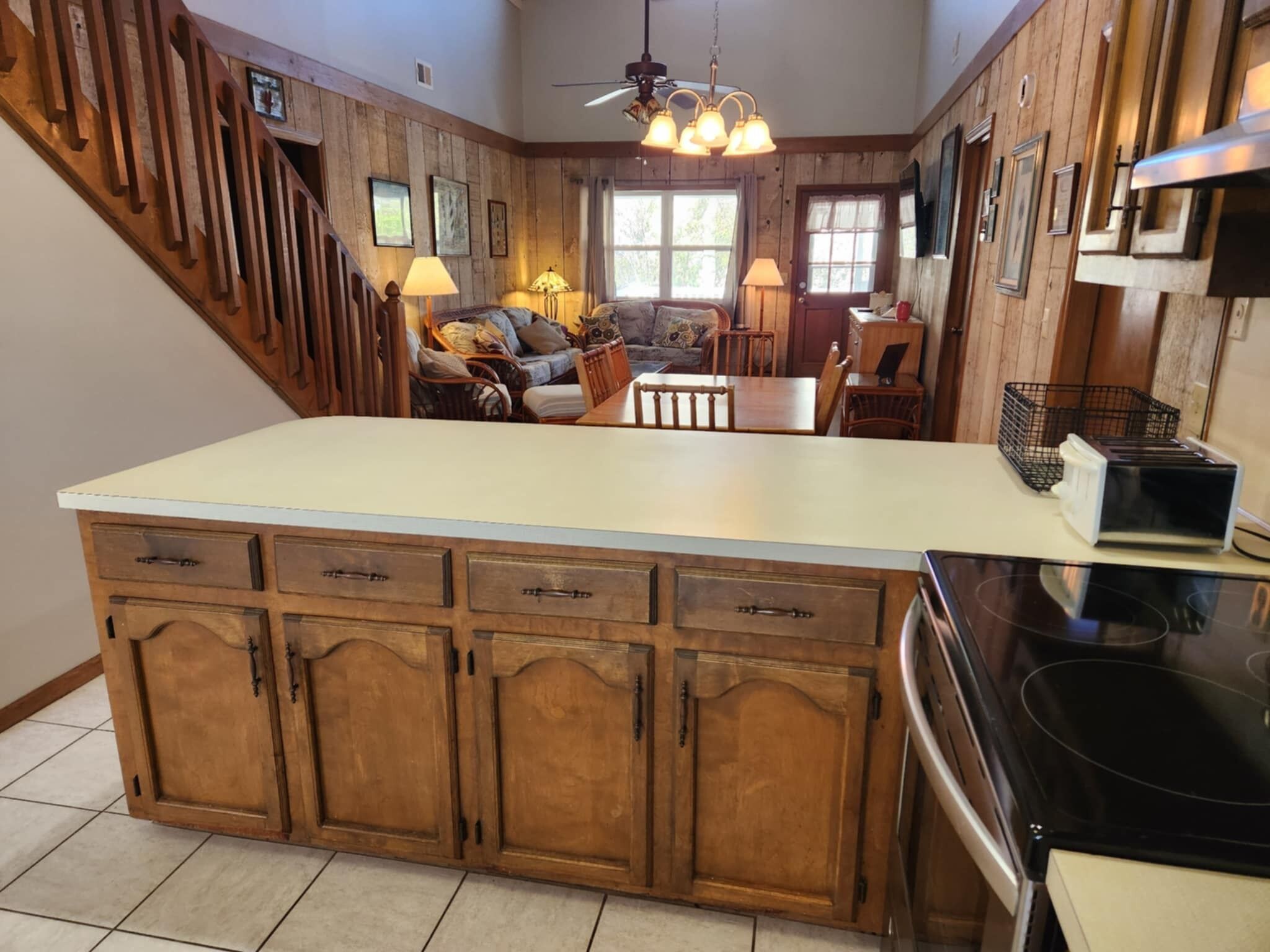 A kitchen with wooden cabinets, a central island, and a dining area with a sofa and chairs.