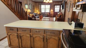 A kitchen with wooden cabinets, a central island, and a dining area with a sofa and chairs.