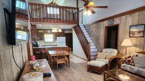 A spacious living area with a wooden staircase, a dining table, and a cozy seating arrangement. - Spacious Beach House Steps to Sand in delightful Ocean Isle Beach NC (Ocean Isle Beach)
