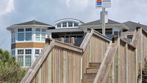 A wooden staircase leading to a beach house with a sign indicating public beach access. - Spacious Beach House Steps to Sand in delightful Ocean Isle Beach NC (Ocean Isle Beach)