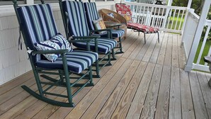 A wooden deck with four striped chairs and a small table. - Spacious Beach House Steps to Sand in delightful Ocean Isle Beach NC (Ocean Isle Beach)