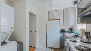 A compact kitchen with white appliances, a stove, and cabinets.